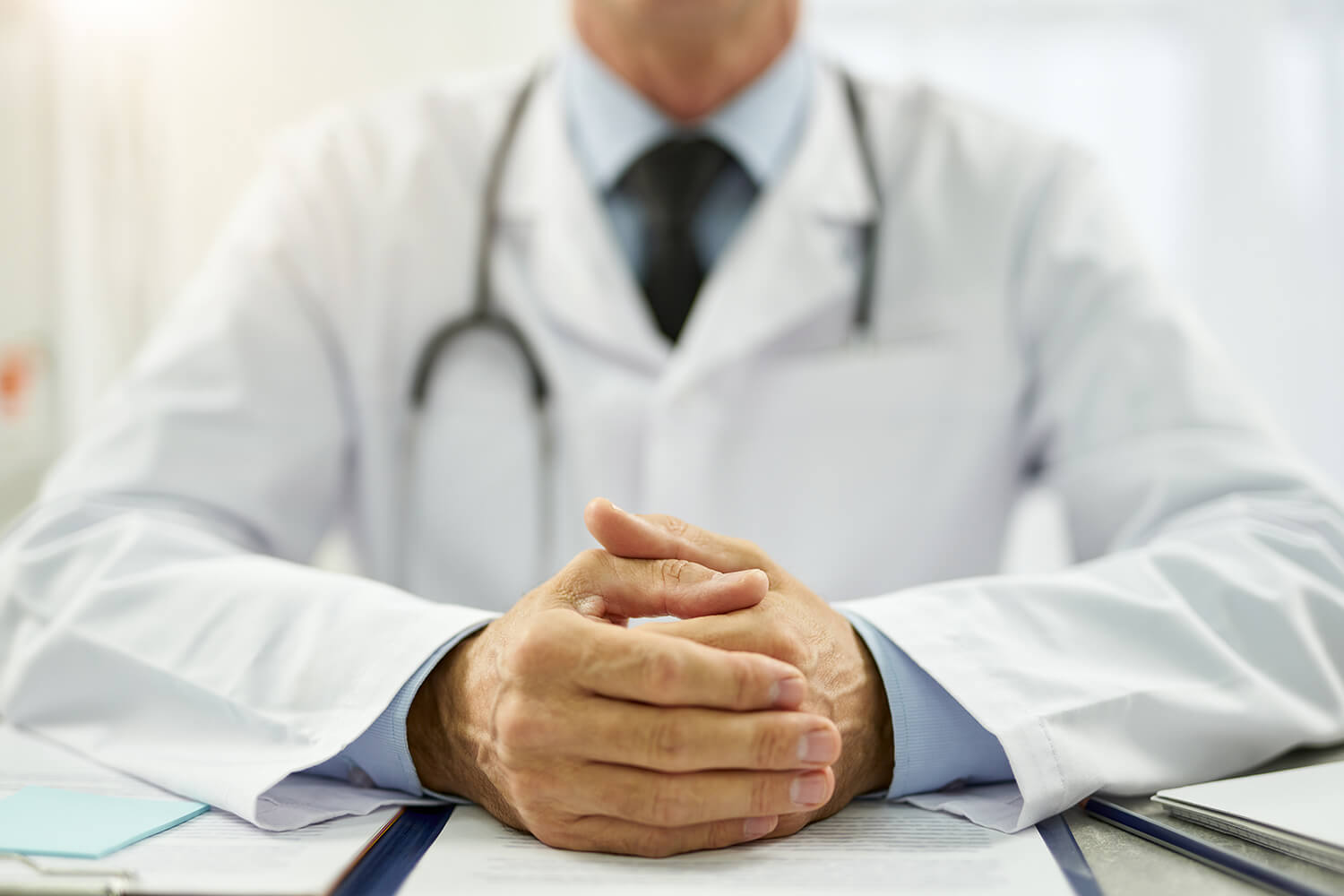 male-doctor-putting-hands-on-table-with-documents